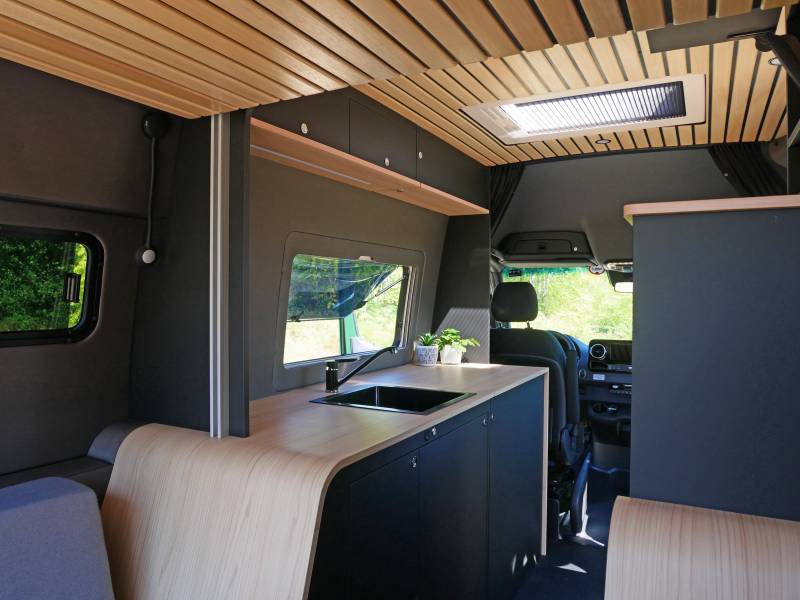 Aménagement sur mesure haut de gamme noir et bois d'un van 4x4